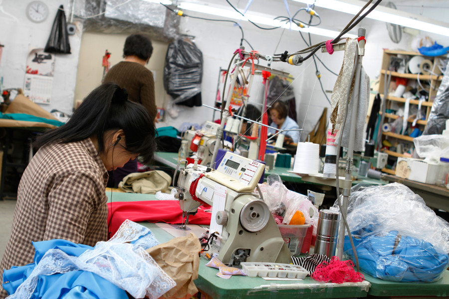 A seamstress works on a garment in the factory Yee contracts to produce her line. While the final product of high-end fashion is crisp and clean, the beginning stages can easily be described as creative chaos.